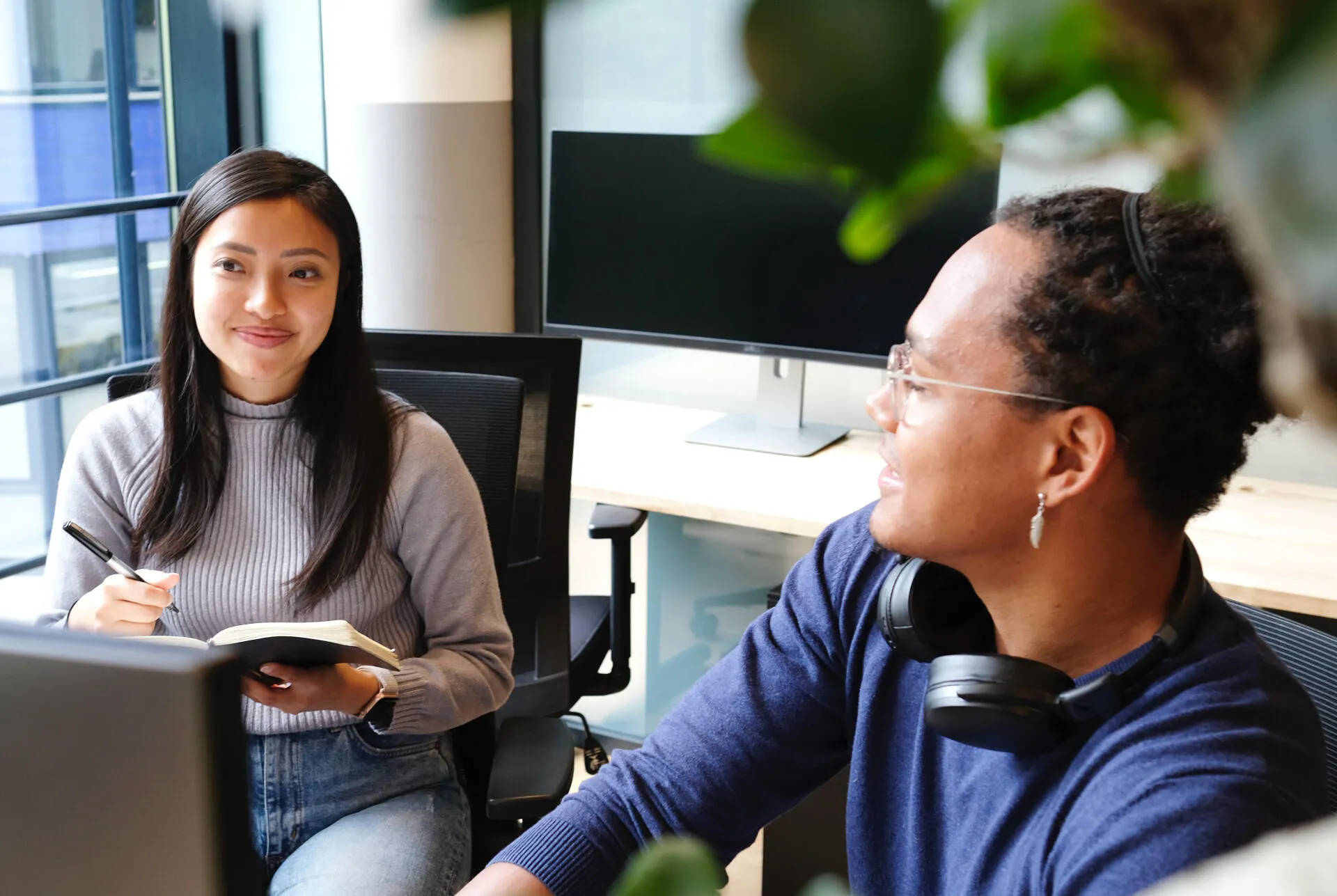 Two colleagues talking at a desk in an office